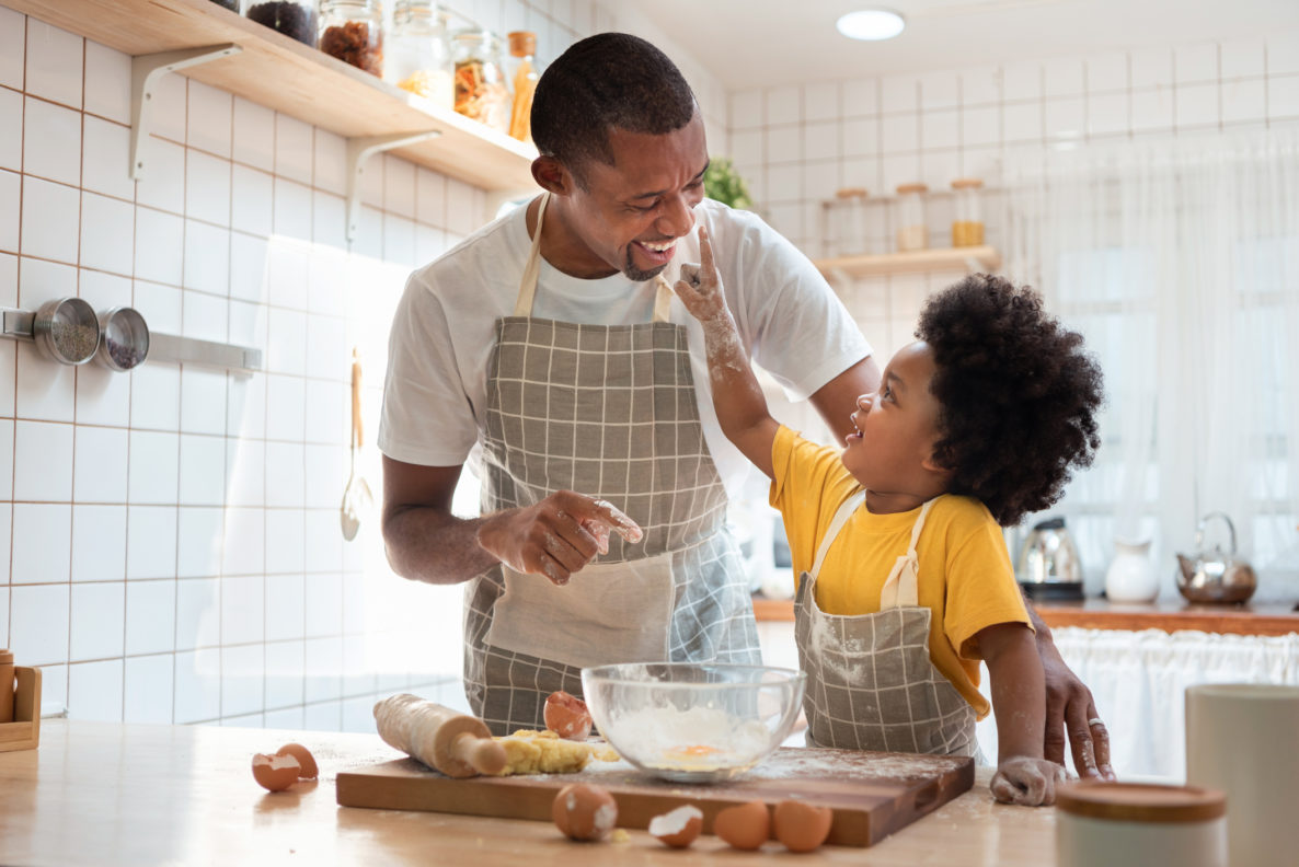 Family have fun cooking baking cake or cookie in the kitchen together, Happy smiling son enjoy playing and touching his father nose with finger and flour while doing bakery at home.